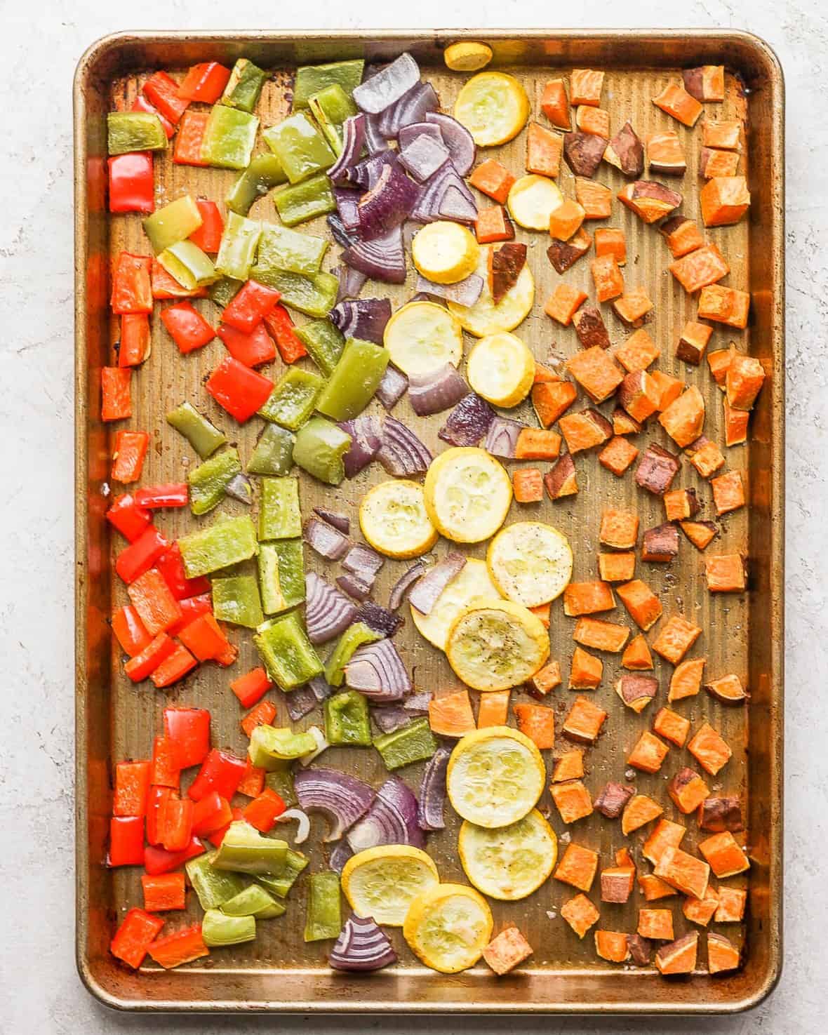 Vegetables on rimmed baking sheet after roasting.