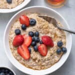 Two bowls of steel cut oatmeal made in the instant pot topped with berries and honey