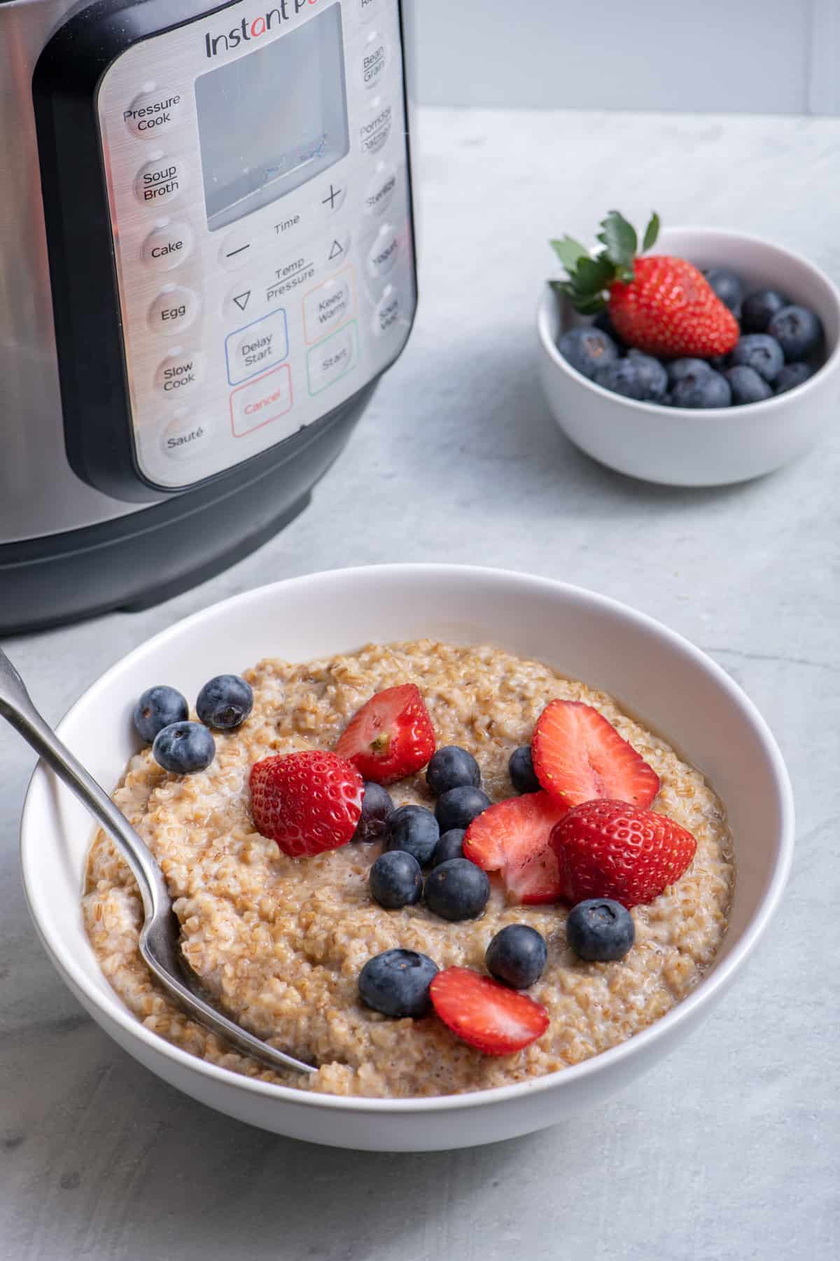 Steel cut oatmeal bowl with a spoon and the instant pot behind it