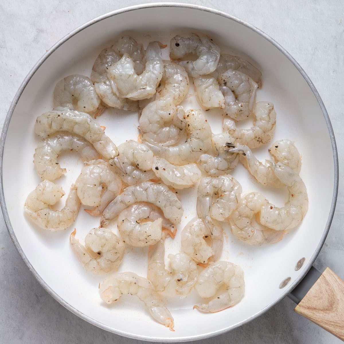 Shrimp in skillet seasoned before cooked.