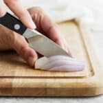 Pairing knife cutting shallot on cutting board