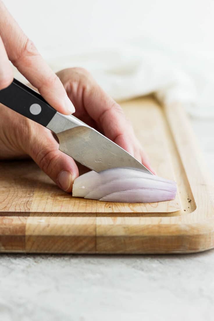 Pairing knife cutting shallot on cutting board