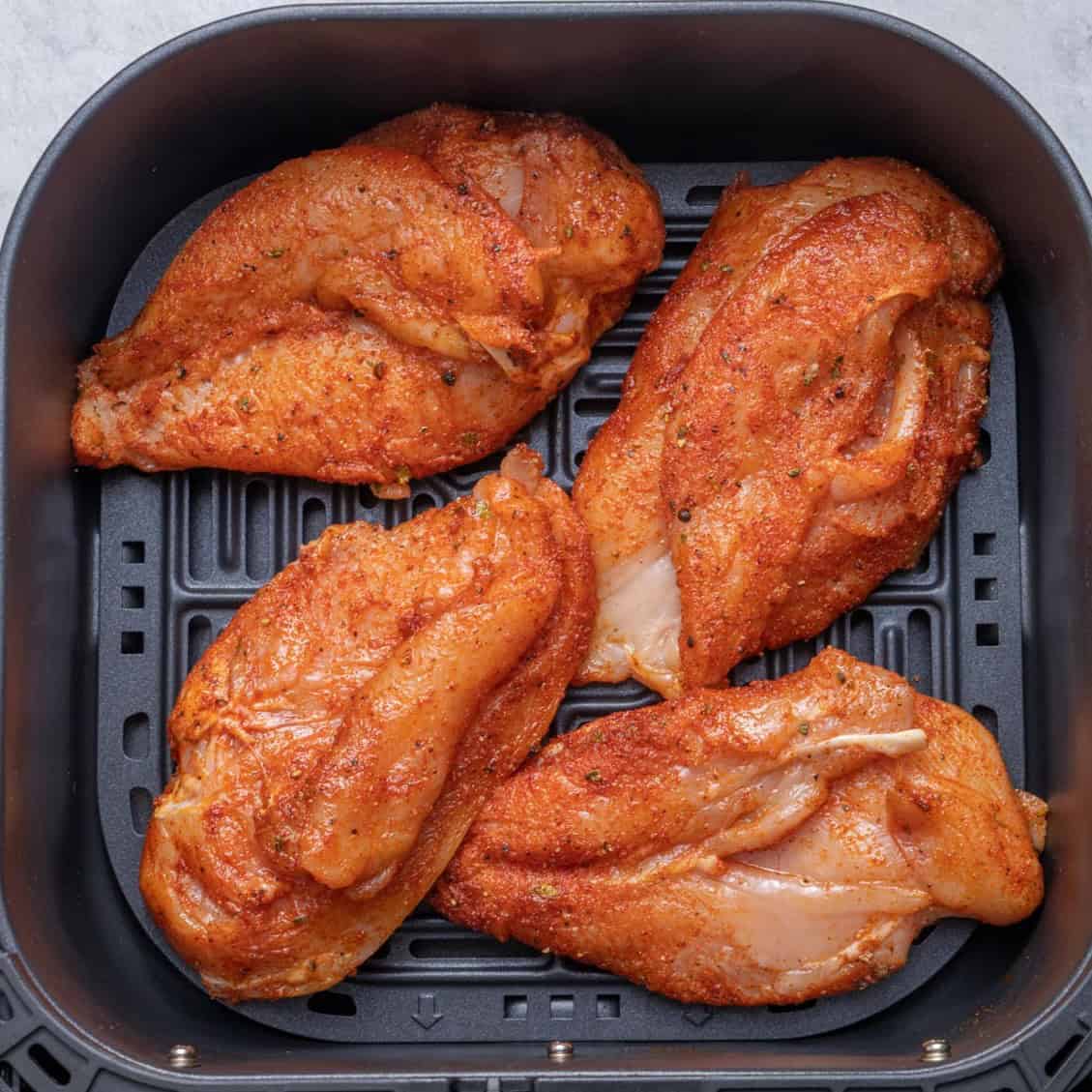Raw chicken placed in an air fryer.
