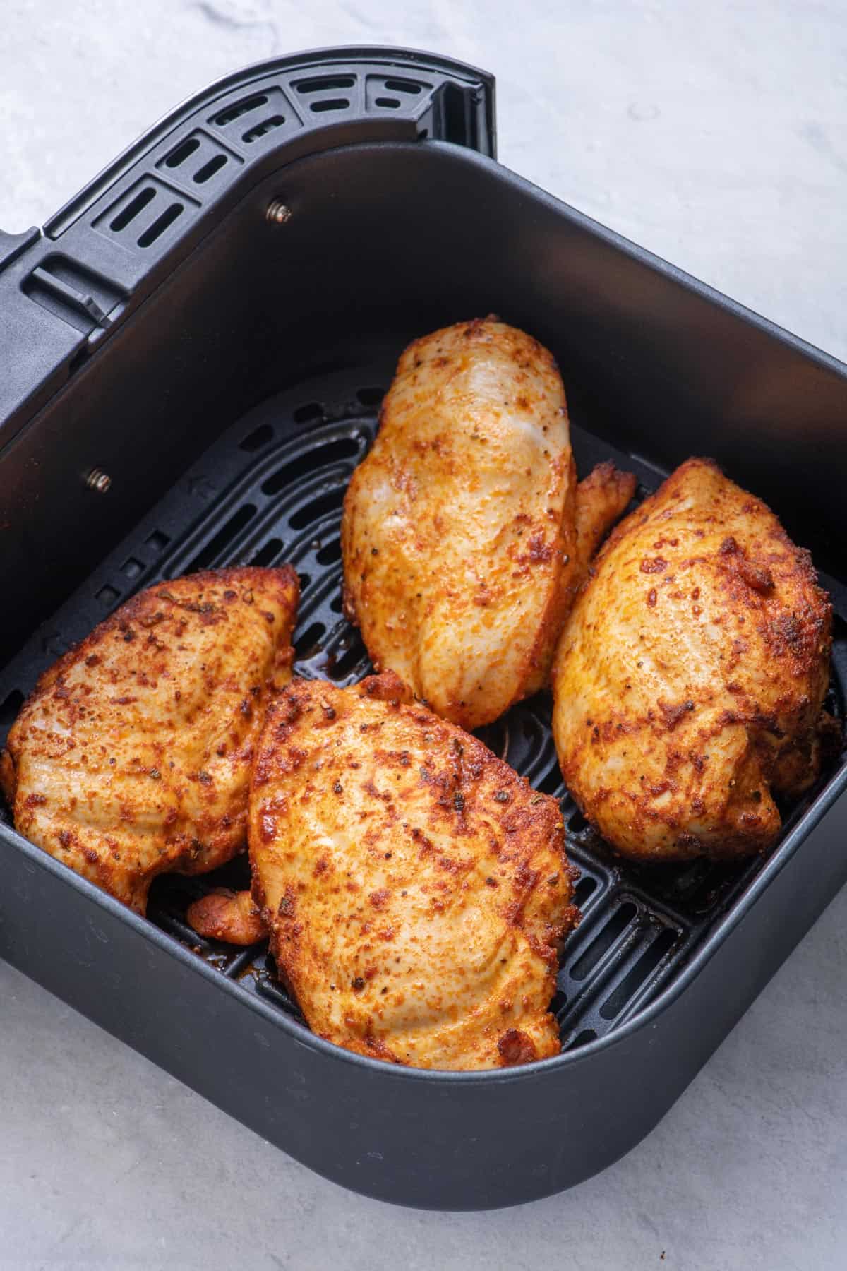 Chicken cooked in the air fryer sitting the basket