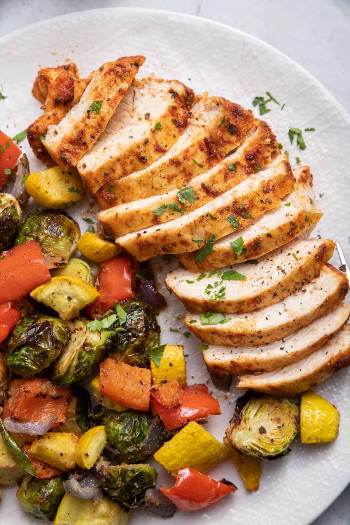 Air fried chicken sliced on a plate with vegetables