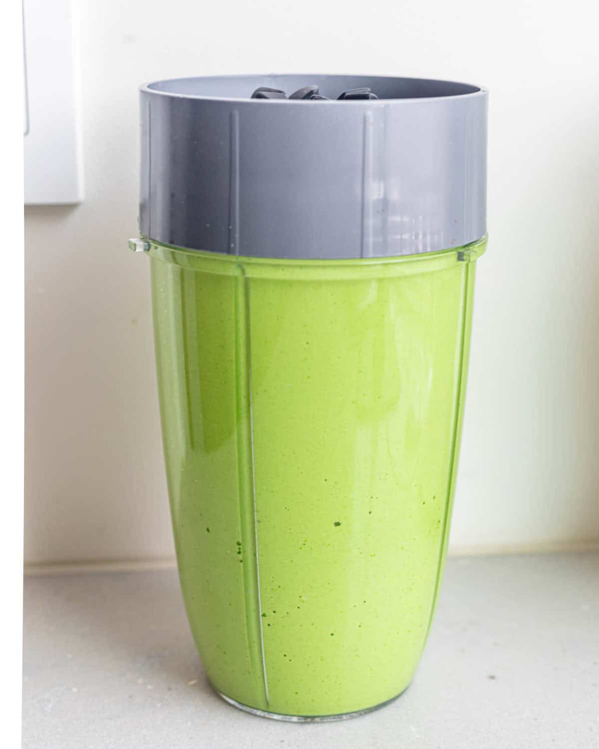 Green goddess salad dressing inside of a blender after blending.