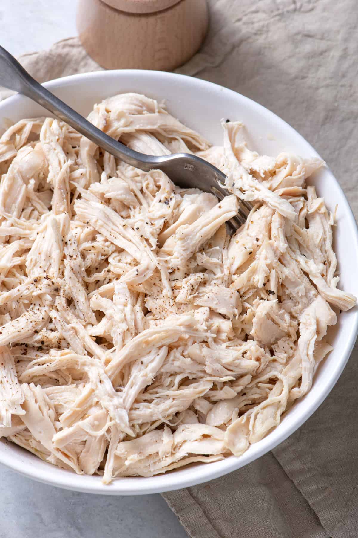 Large bowl of shredded chicken with fork in bowl