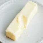 Butter on small plate after microwaving with indented finger mark.