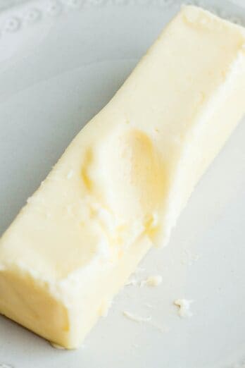 Butter on small plate after microwaving with indented finger mark.