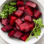 Chopped beets in a white bowl with parsley after steaming