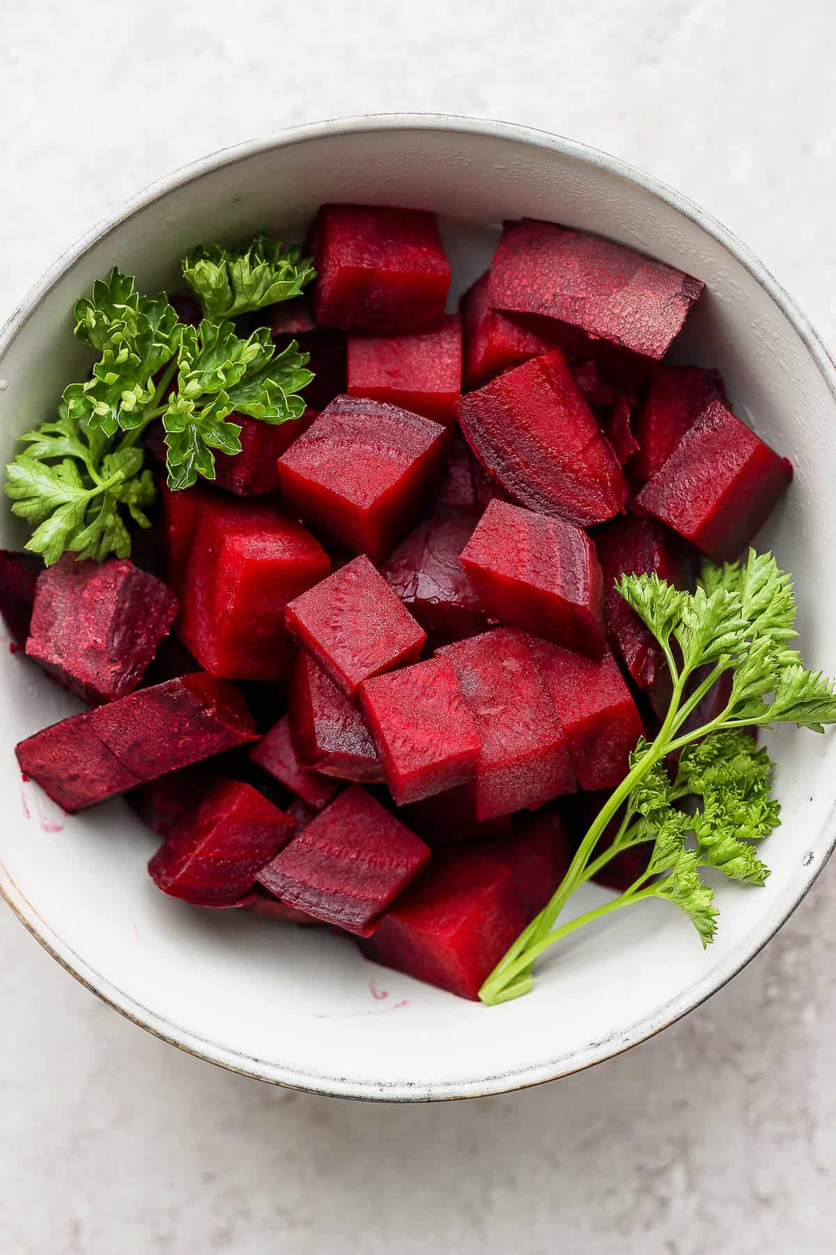 Chopped beets in a white bowl with parsley after steaming