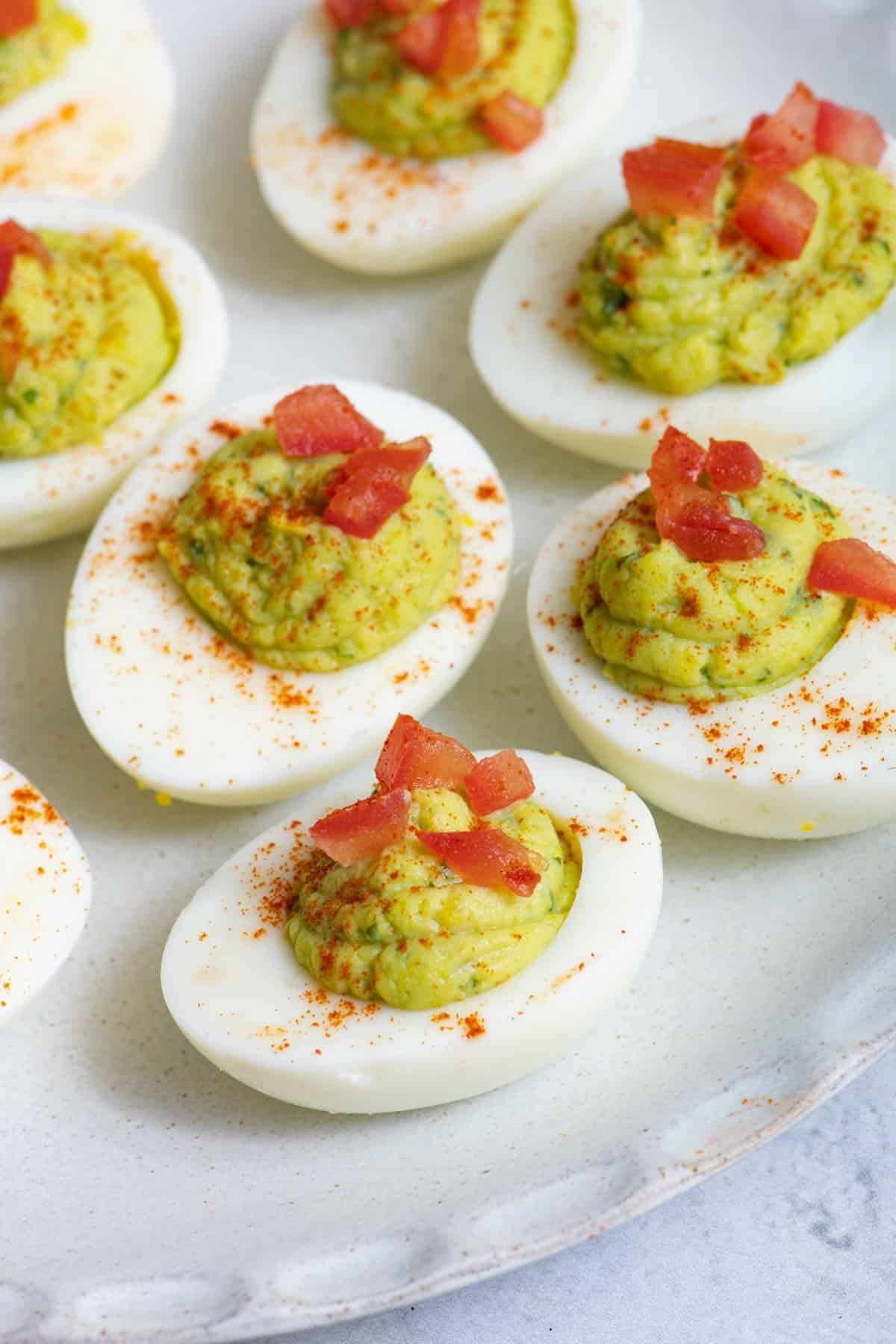 a few avocado deviled eggs with diced tomatoes and chili powder sprinkled on top