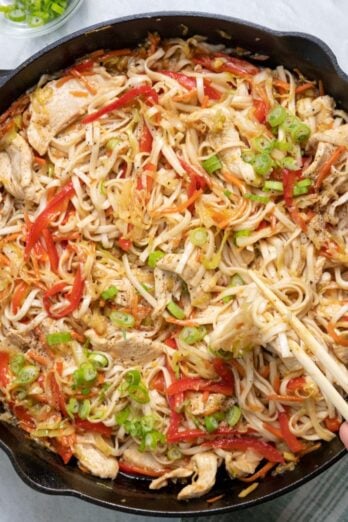 Everything tossed together with some green onions garlic on top and chopsticks resting inside.