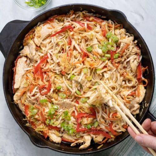 Everything tossed together with some green onions garlic on top and chopsticks resting inside.