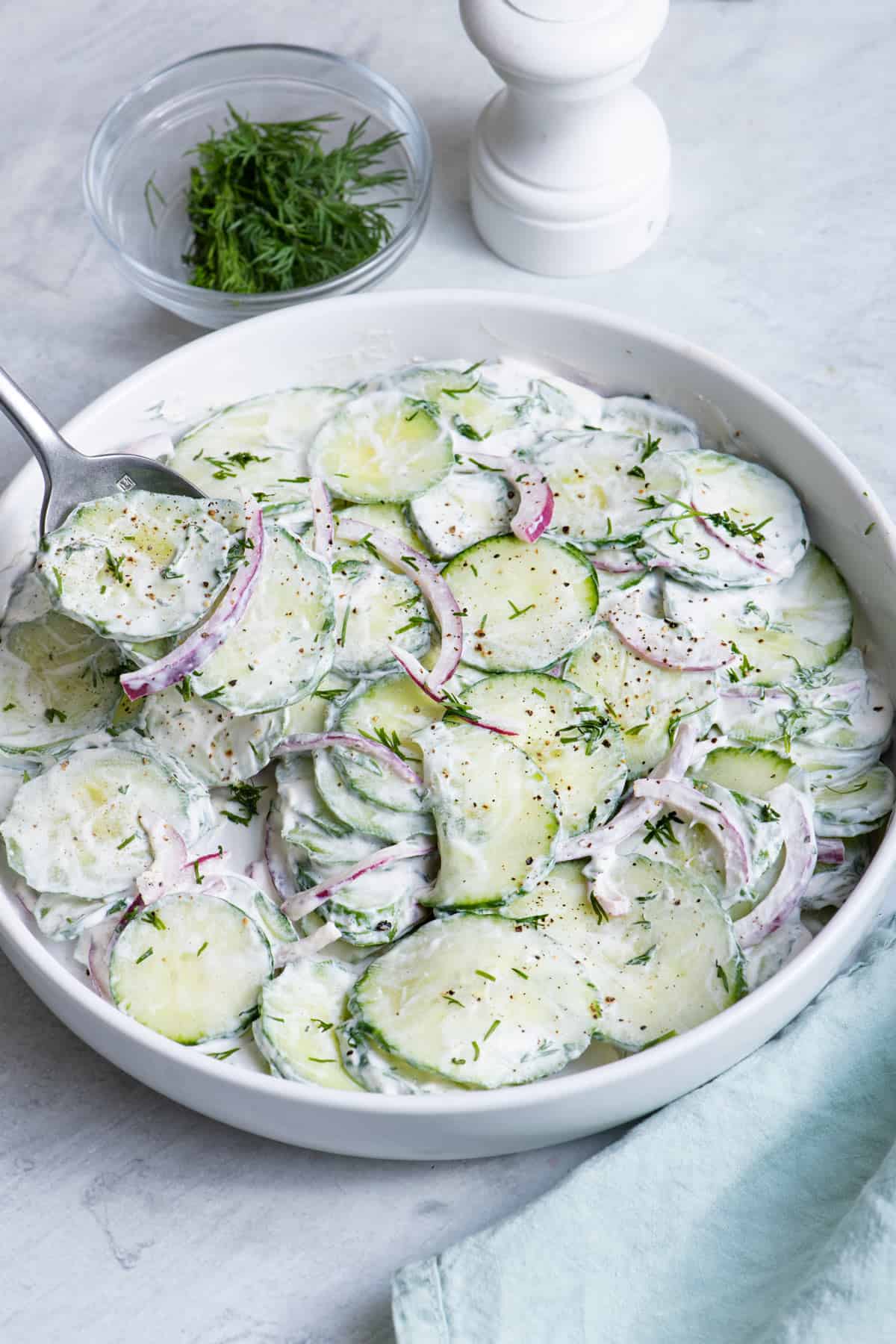 spoon grabbing a bite from a bowl of cucumber salad