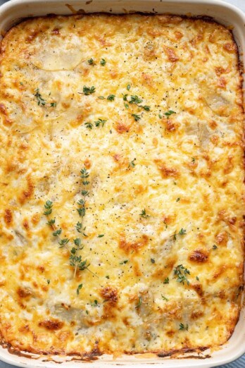 Scalloped potatoes after done baking garnished with fresh thyme leaves and black pepper.
