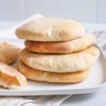 stack of freshly baked homemade pita bread on white square plate