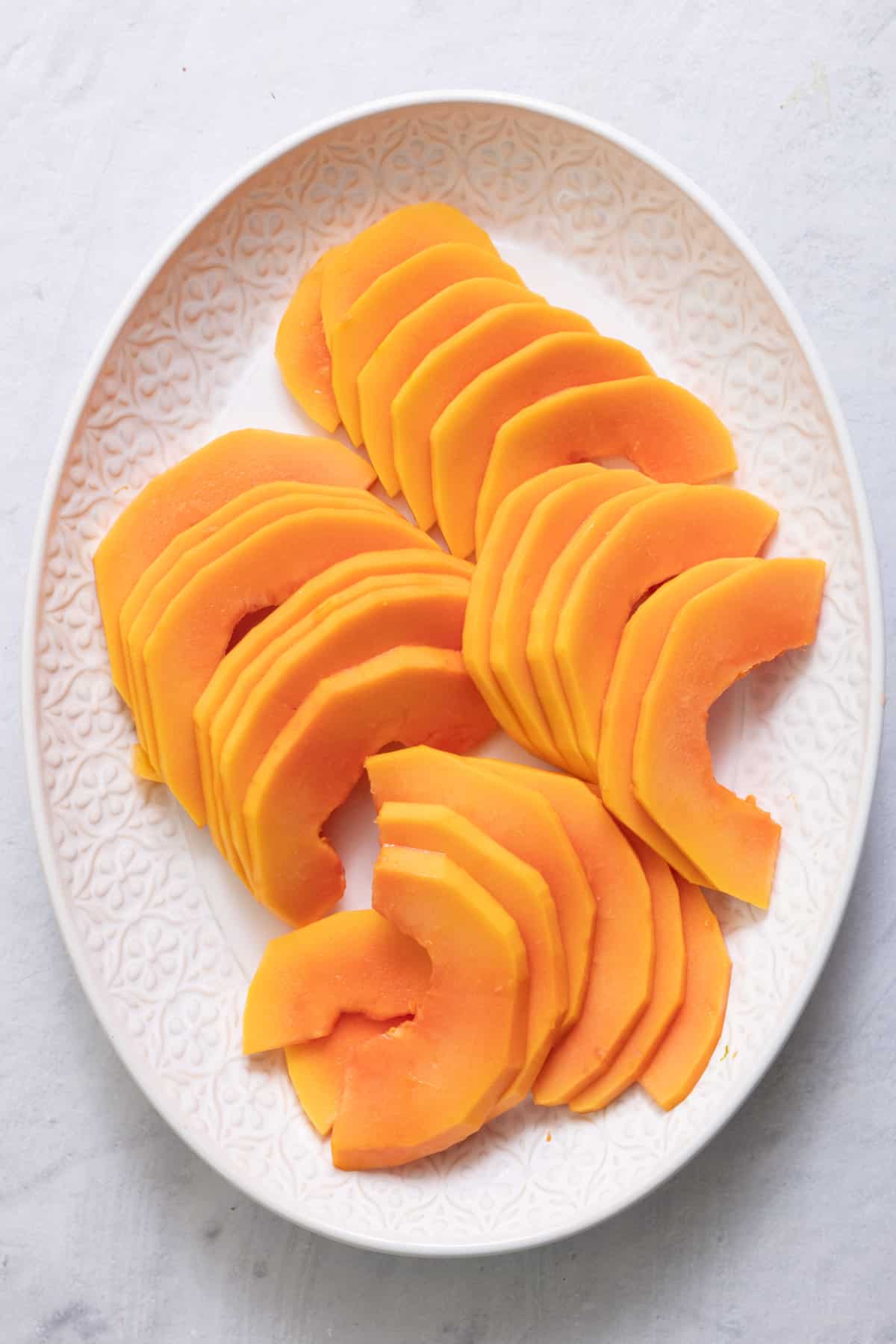 large white oval plate with slices of papaya