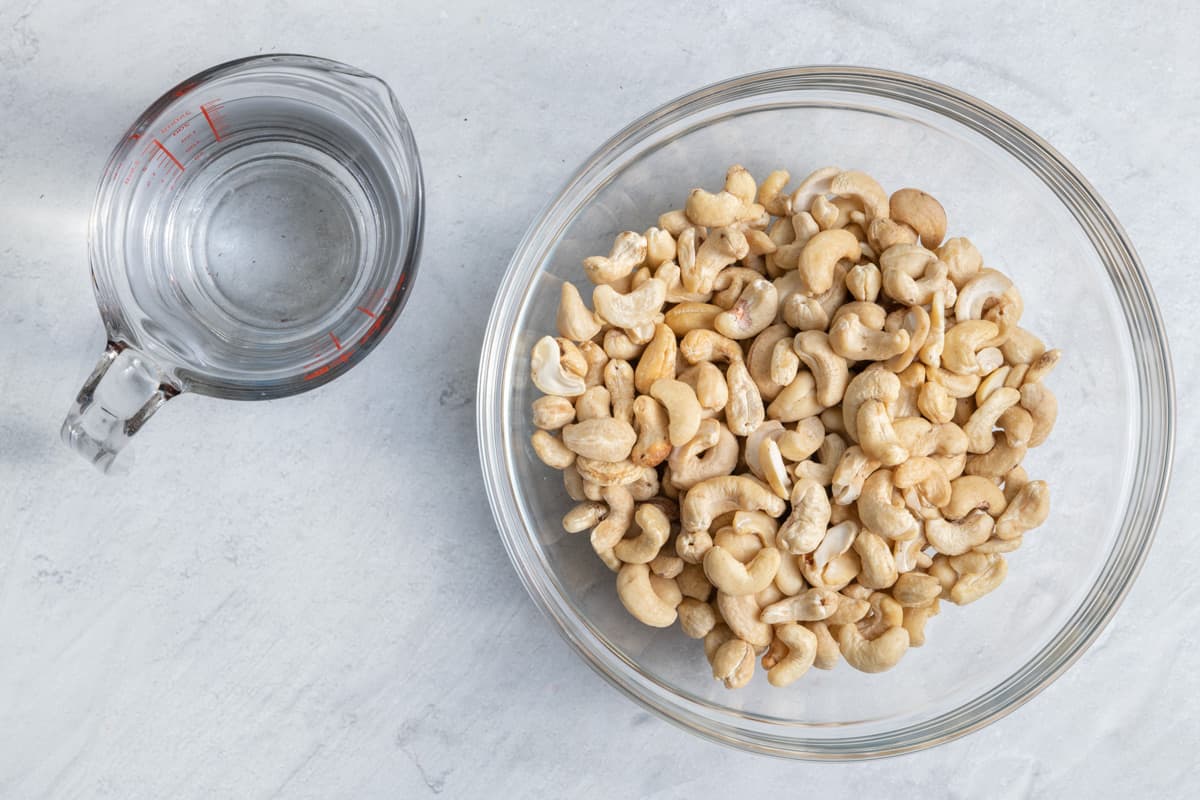 ingredients for recipe with cashews in a bowl and measuring cup with water