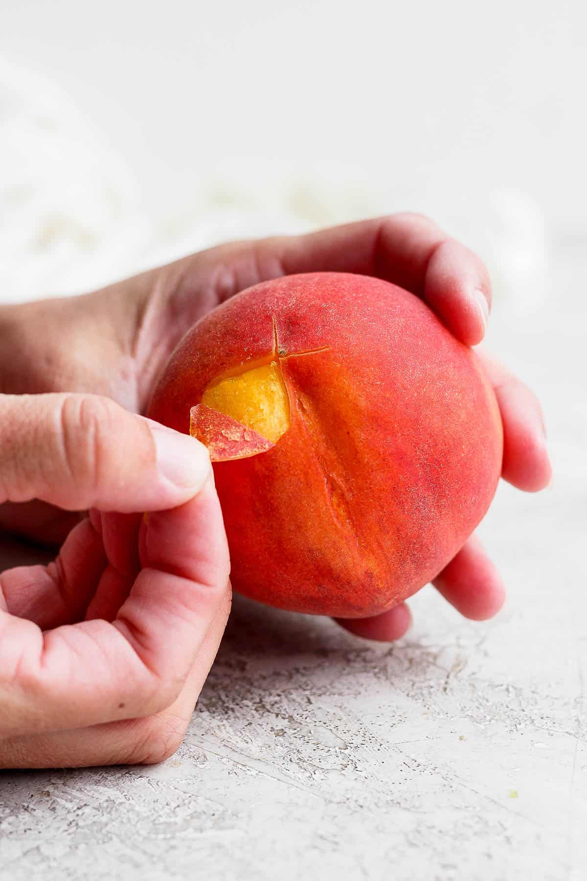 Hand peeling back skin of a peach