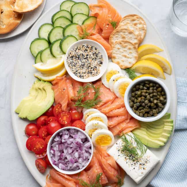 Smoked salmon platter with eggs, cucumber, avocado, tomatoes, crackers and more