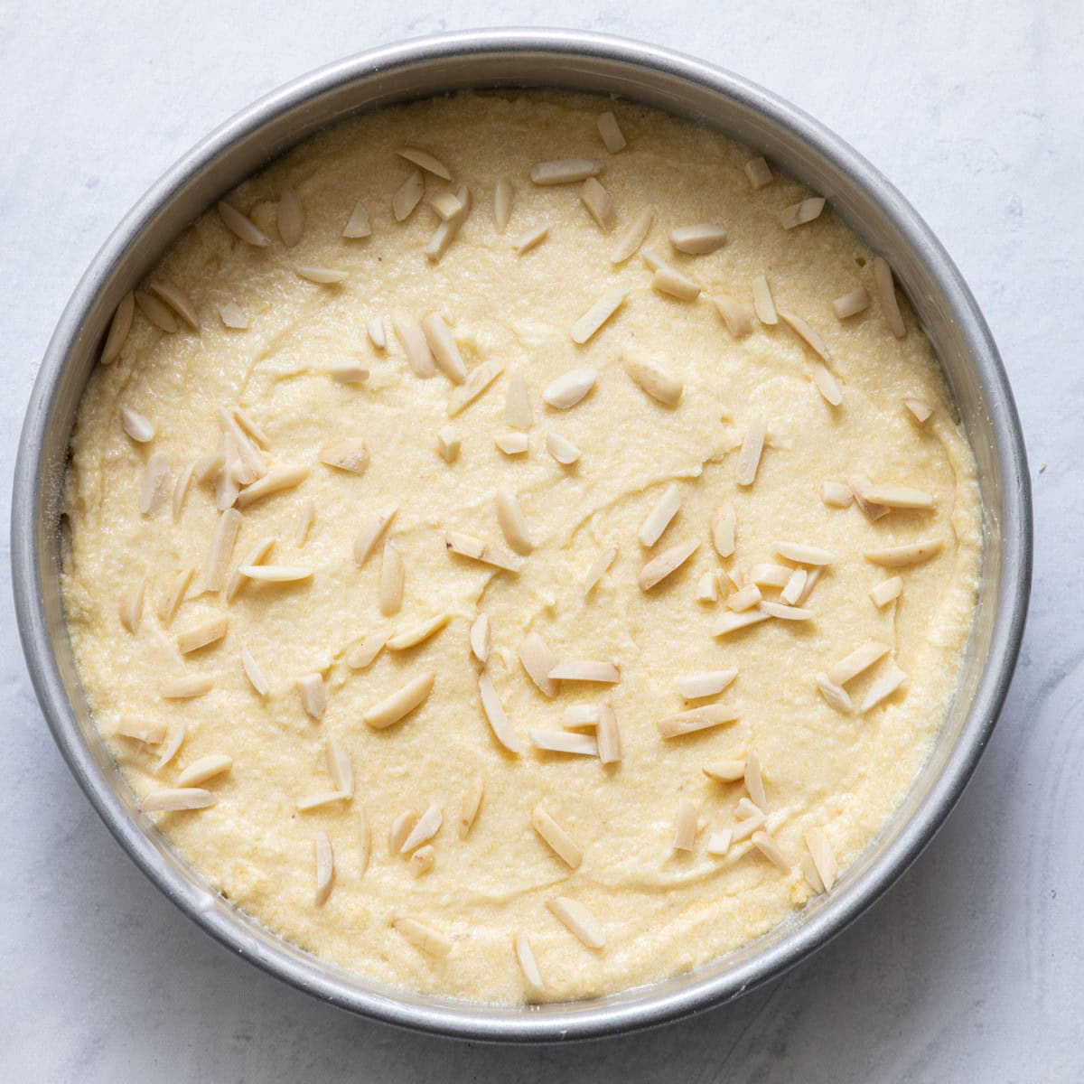 Batter in prepared baking pan with silvered almonds and sugar sprinkled on top.