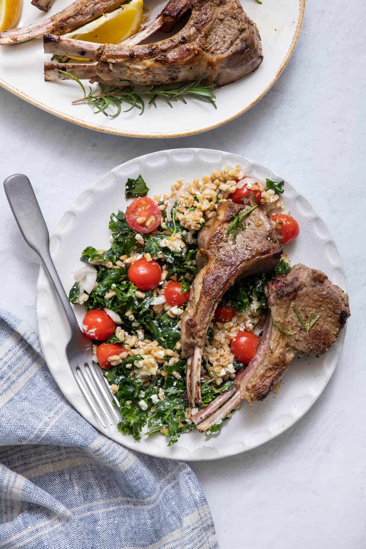 Two lamb chops served on a plate with farro salad.