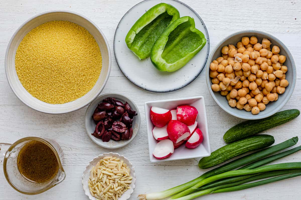 Ingredients for recipe: Moroccan couscous, chickpeas, persian cucumbers, green peppers, radish, slivered almonds, olives, and green onions.