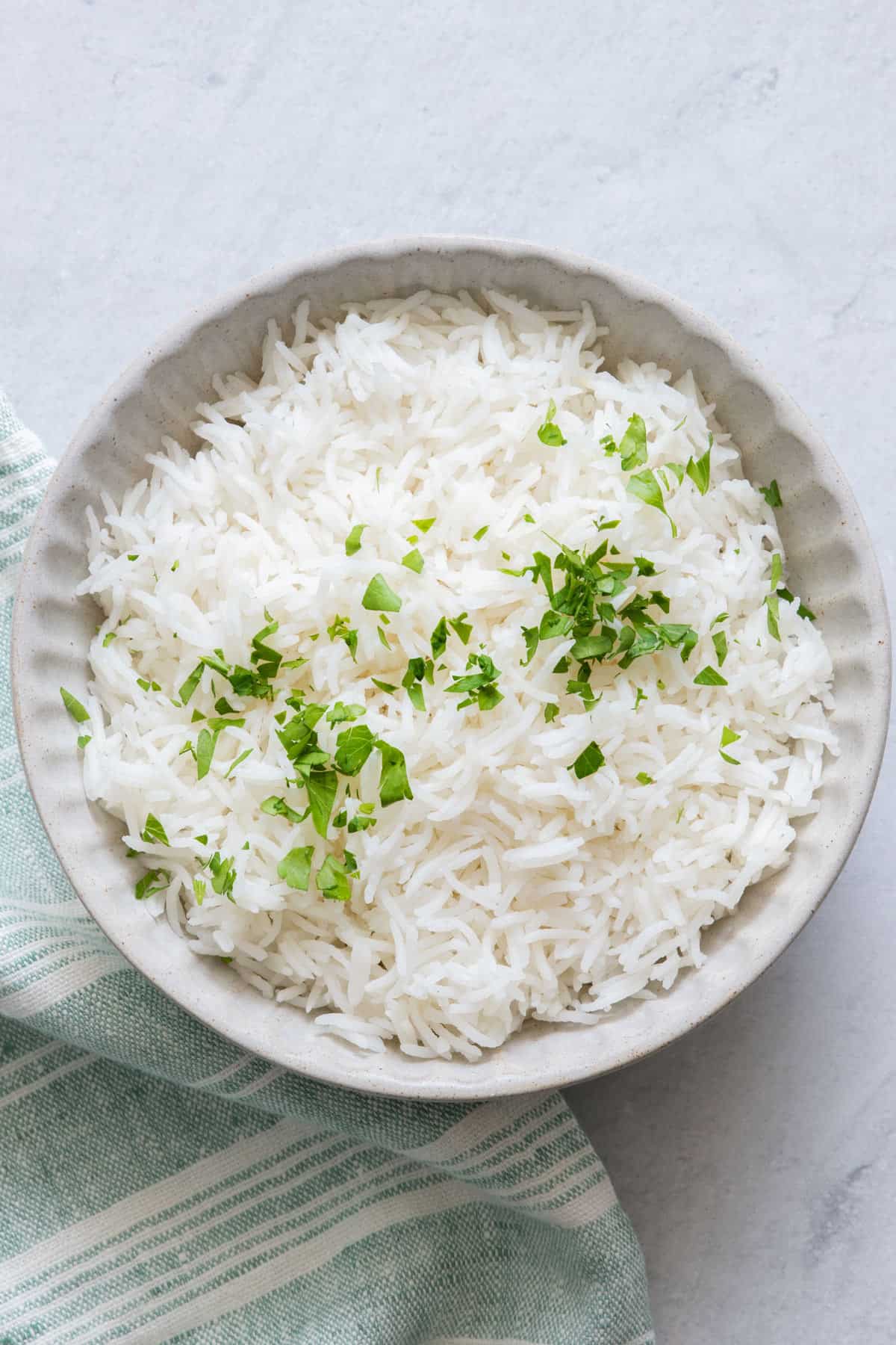 White bowl of Basmati rice garnished with chopped parsley.