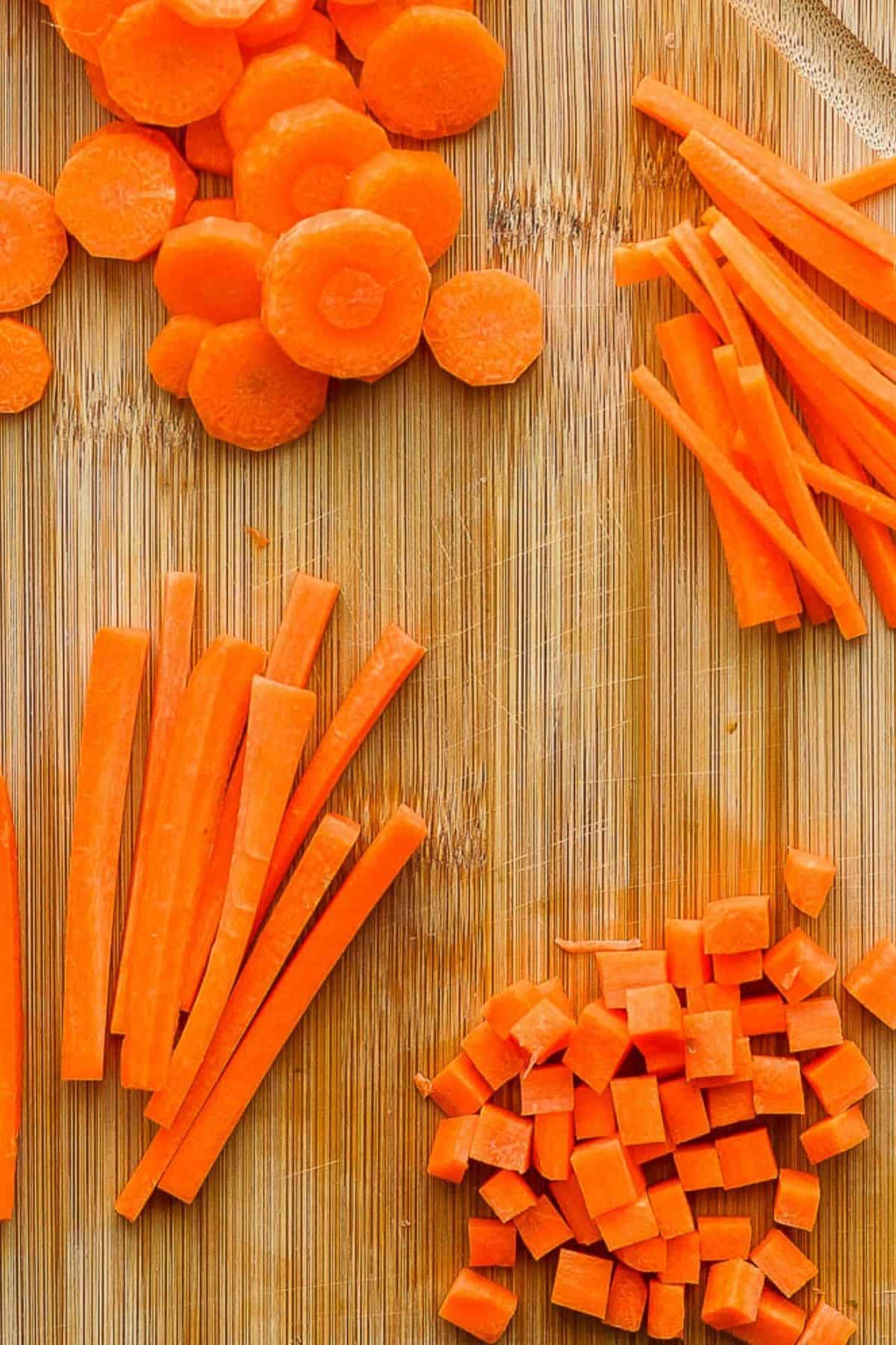 Close up of carrots cut in different ways on a cutting board.