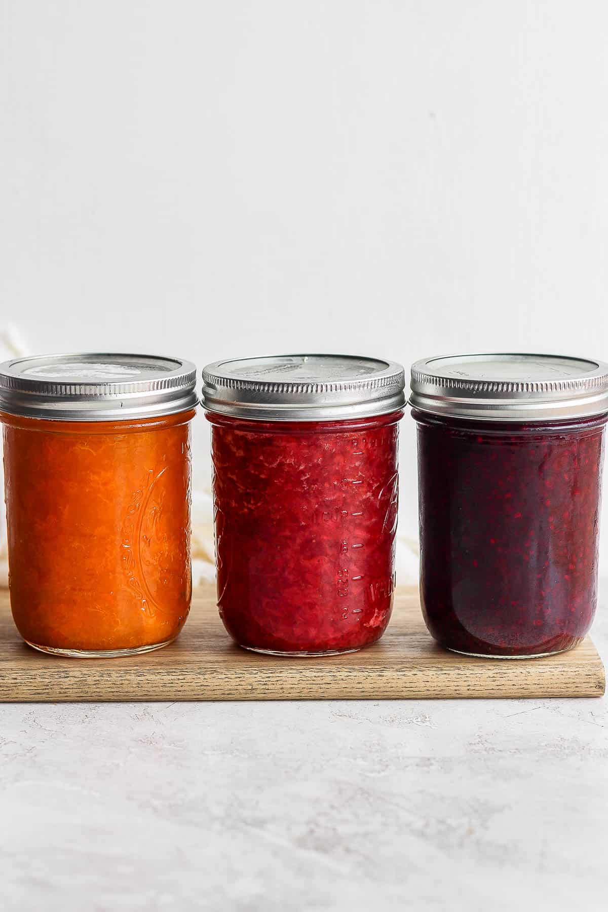 3 mason jars filled with homemade fruit jams in different flavors.