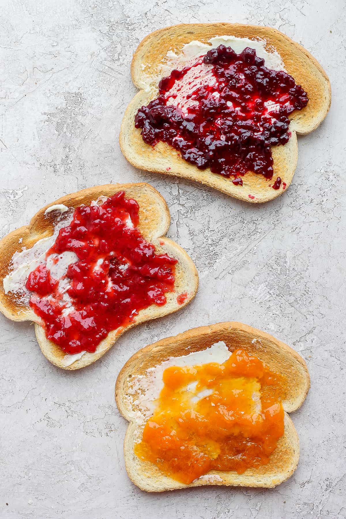 3 pieces of toast with butter and different flavored jams on each.
