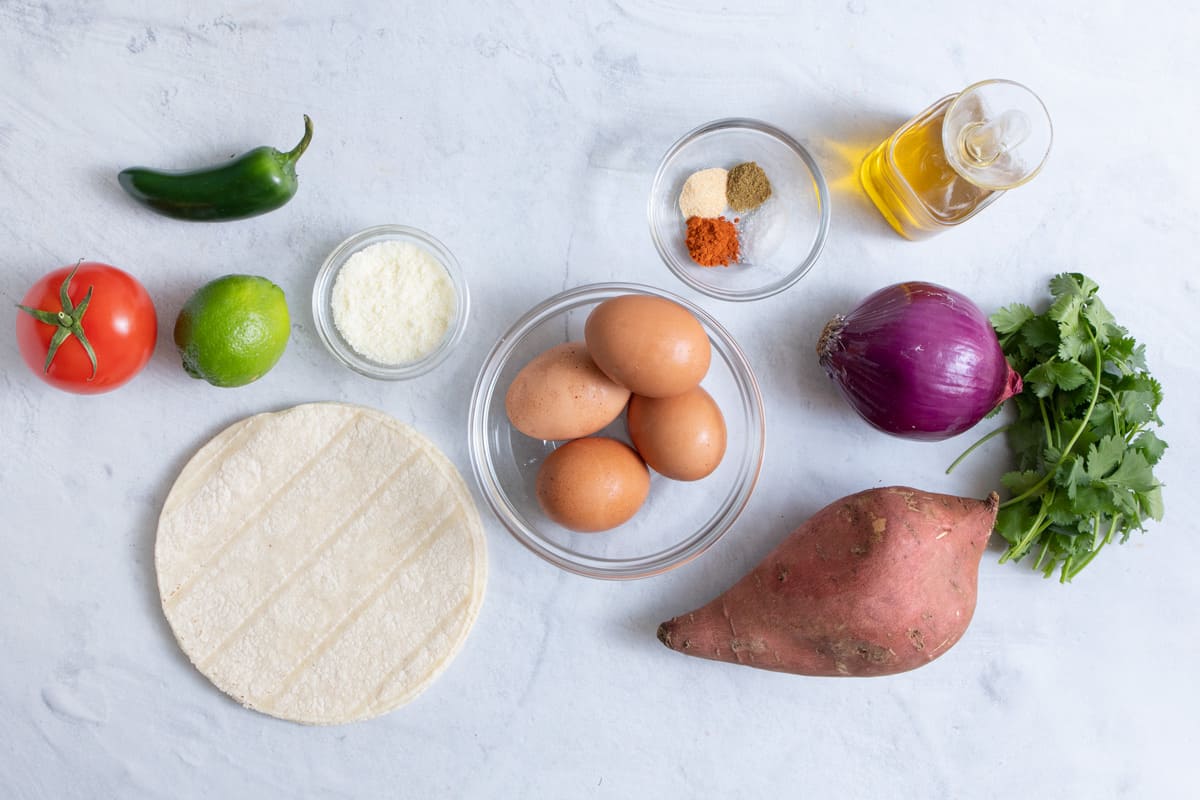 Ingredients for recipe: tortilla shells, tomato, lime, jalepno, cojito cheese, eggs, spices, oil, onion, sweet potato, and cilantro.