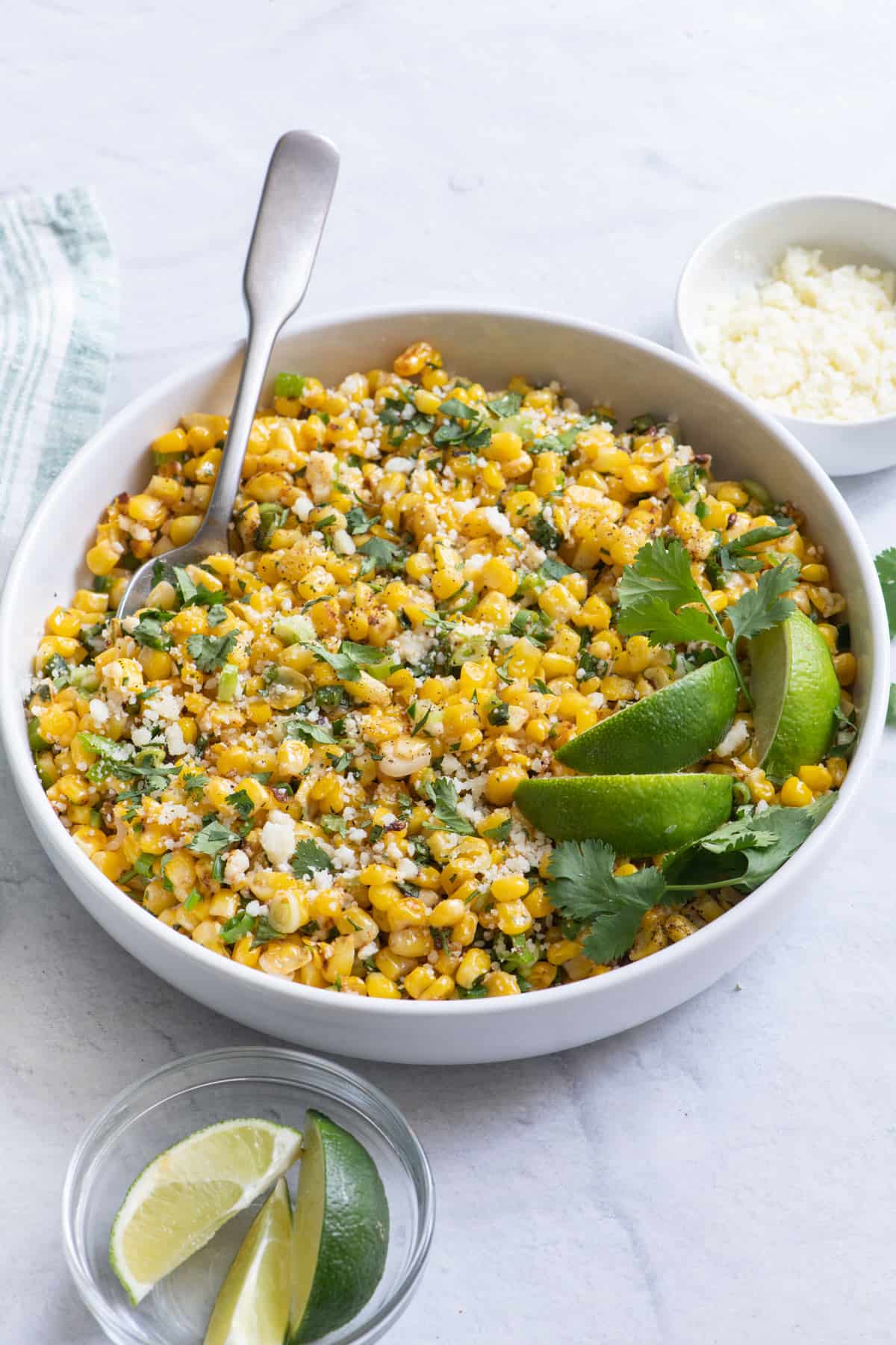 Angled shot of corn salad in large serving bowl with spoon.