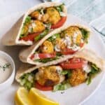 Three cauliflower pitas on a dish resting on top of one another with a small dish of tahini nearby.