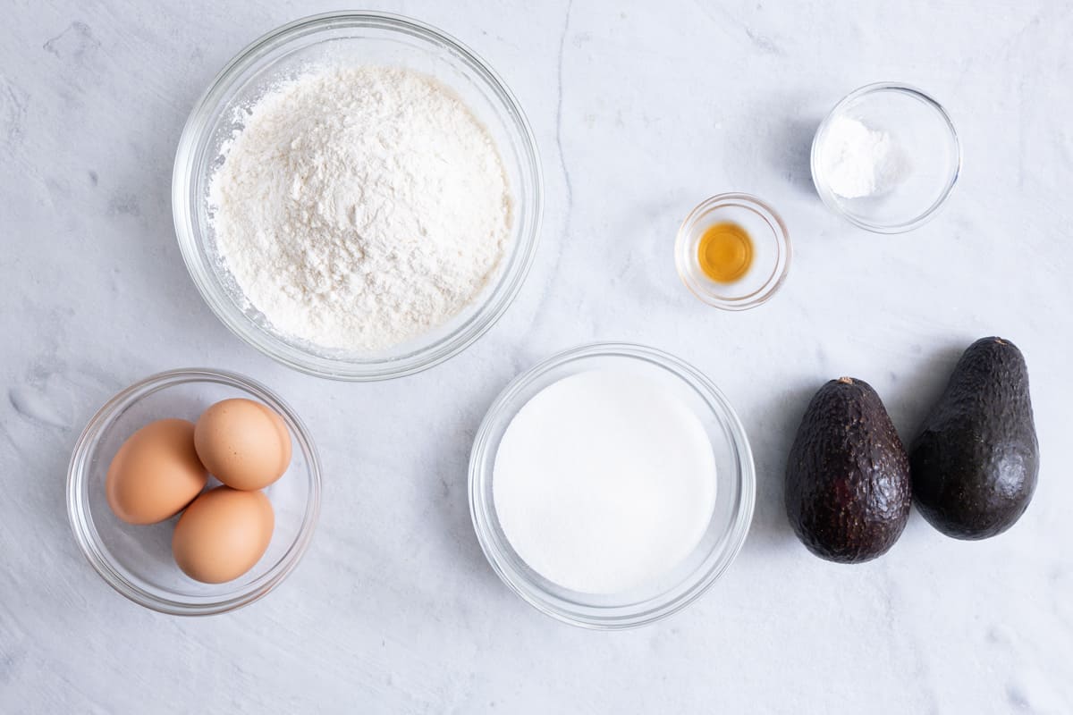 Ingredients for bread recipe: eggs, flour ,sugar, vanilla, baking powder, and two avocados.