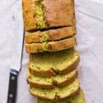 Top view of avocado bread with a few thick slices cut and knife off to side.