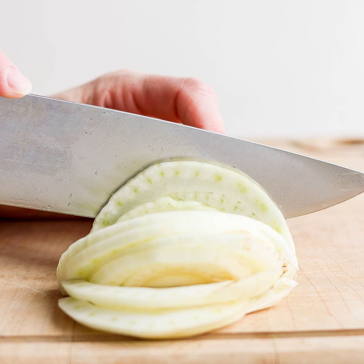 Towards the end of cutting half of a fennel into thin slices.