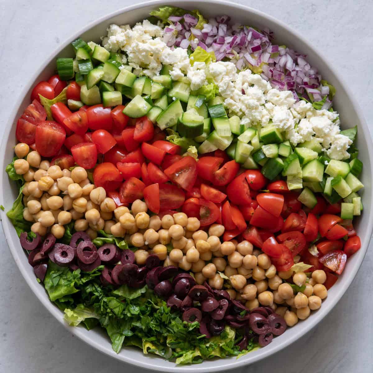 Onions, feta, and olives added on top of the lettuce.