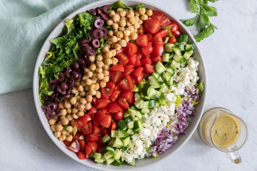 Mediterranean chopped salad assembled in a serving bowl with dressing on the side.