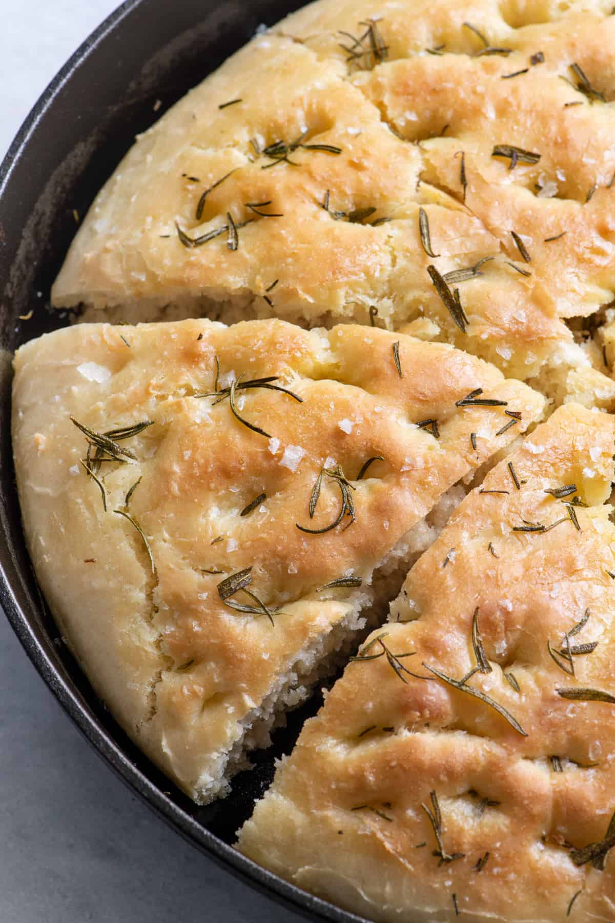 Close up of Focaccia in skillet cut into triangles.