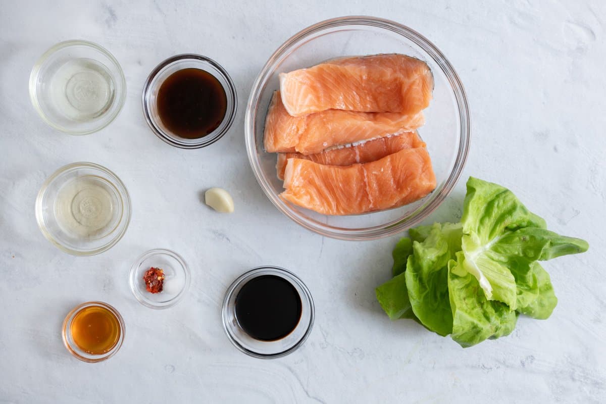 Ingredients for sauce, 4 pieces of salmon filets in bowl, and bibb lettuce leaves.