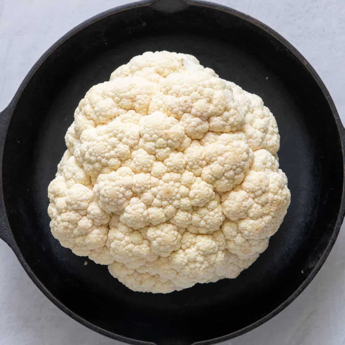 Cauliflower on skillet stem side down.