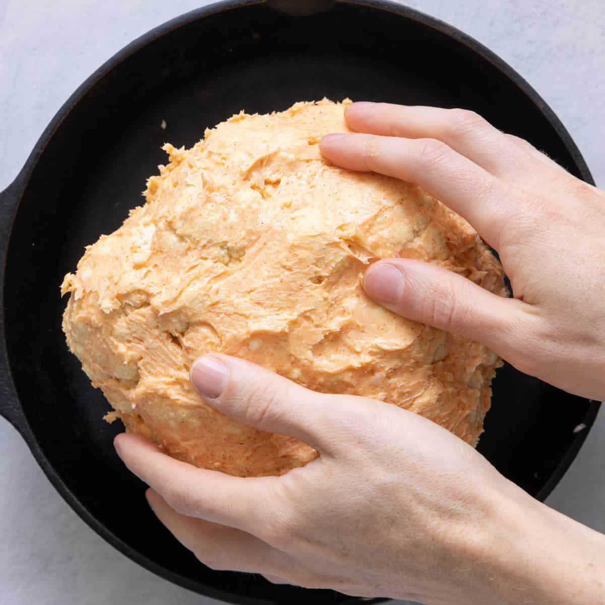Hand rubbing softened butter mixture on cauliflower.