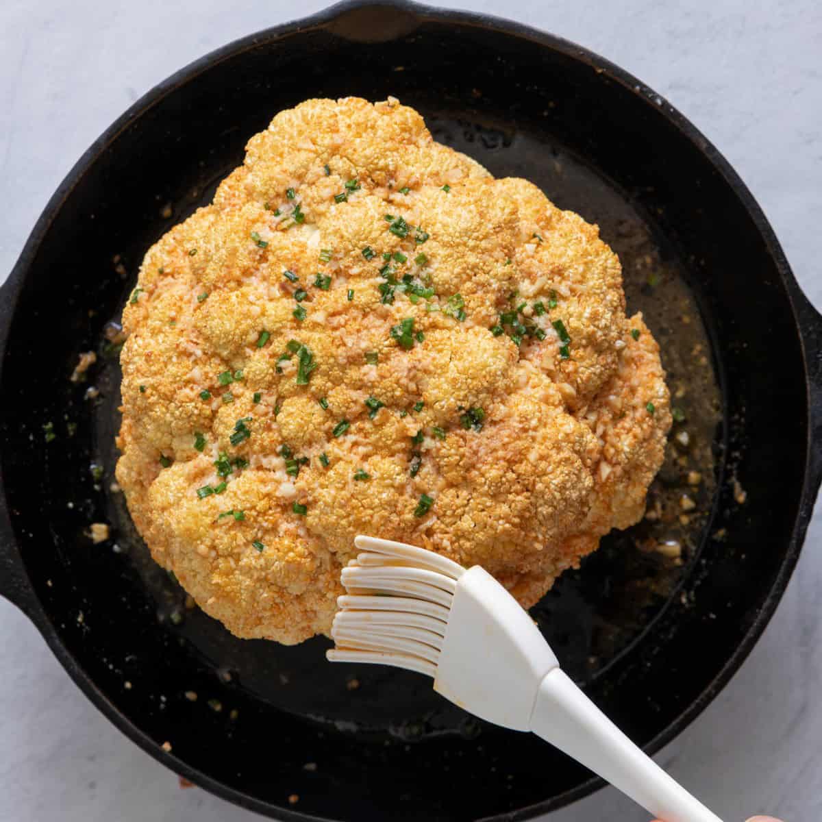Basting cauliflower with melted butter after roasted with parmesan cheese & chives.