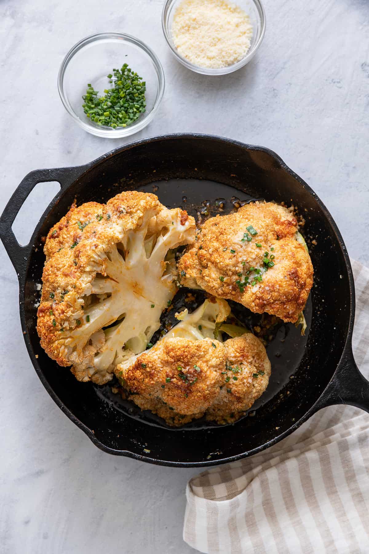 Roasted cauliflower in cast iron skillet cut into large pieces.