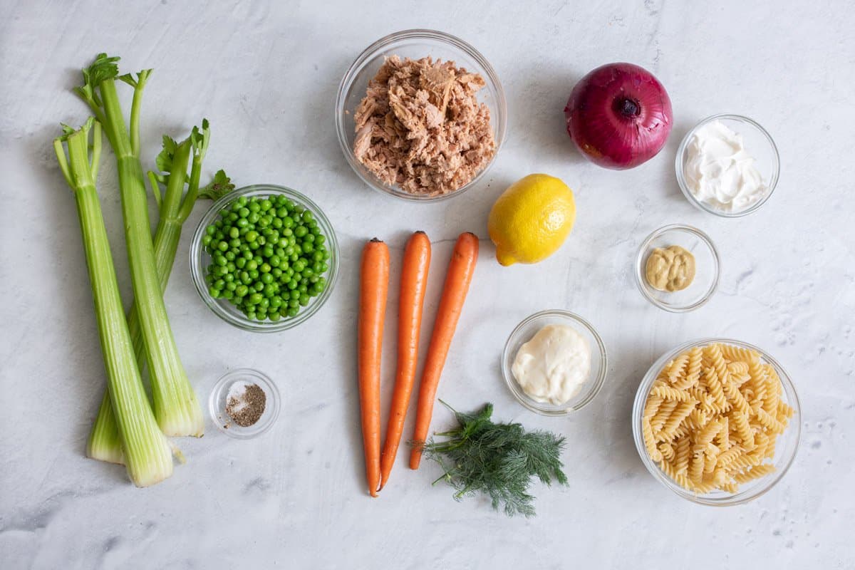 Ingredients for salad recipe: 3 stalks of celery, bowl of beats, salt and pepper, bowl of canned tuna, 3 carrots, whole lemon, fresh dill, mayo, dijon mustard, greek yogurt, and uncooked pasta.
