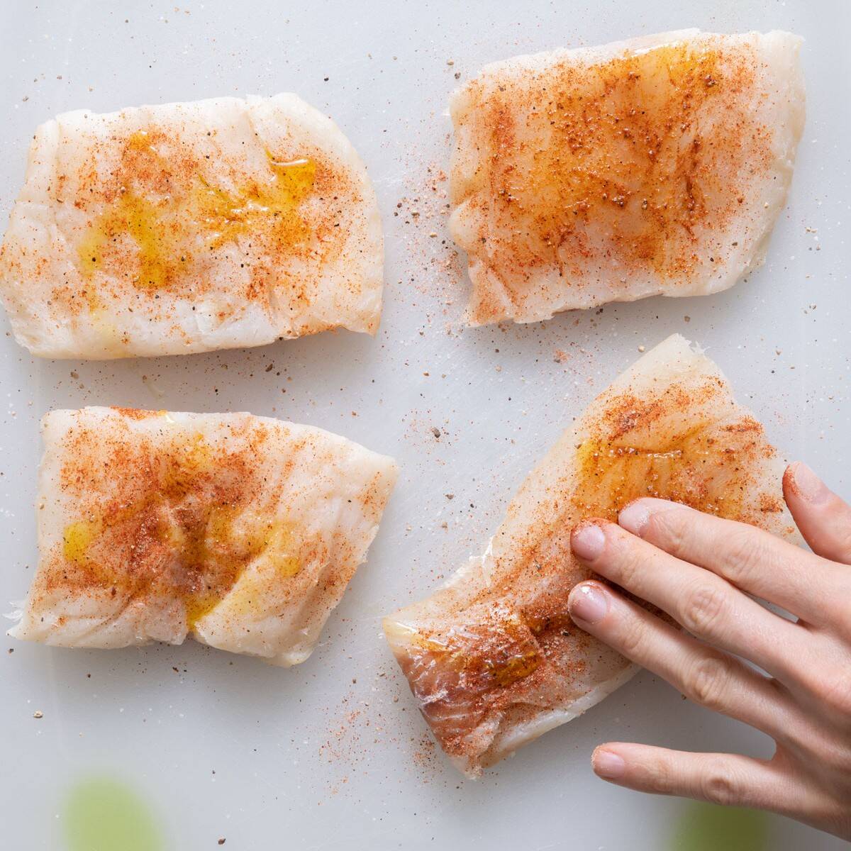 Rubbing olive oil on cod.