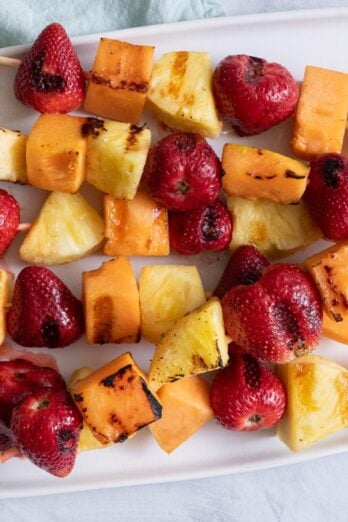 Grilled fruit kabobs laid flat on a serving dish.