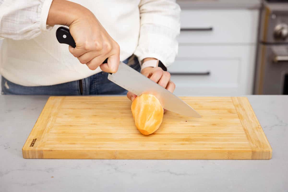 Chef's knife cutting sweet potato on cutting board